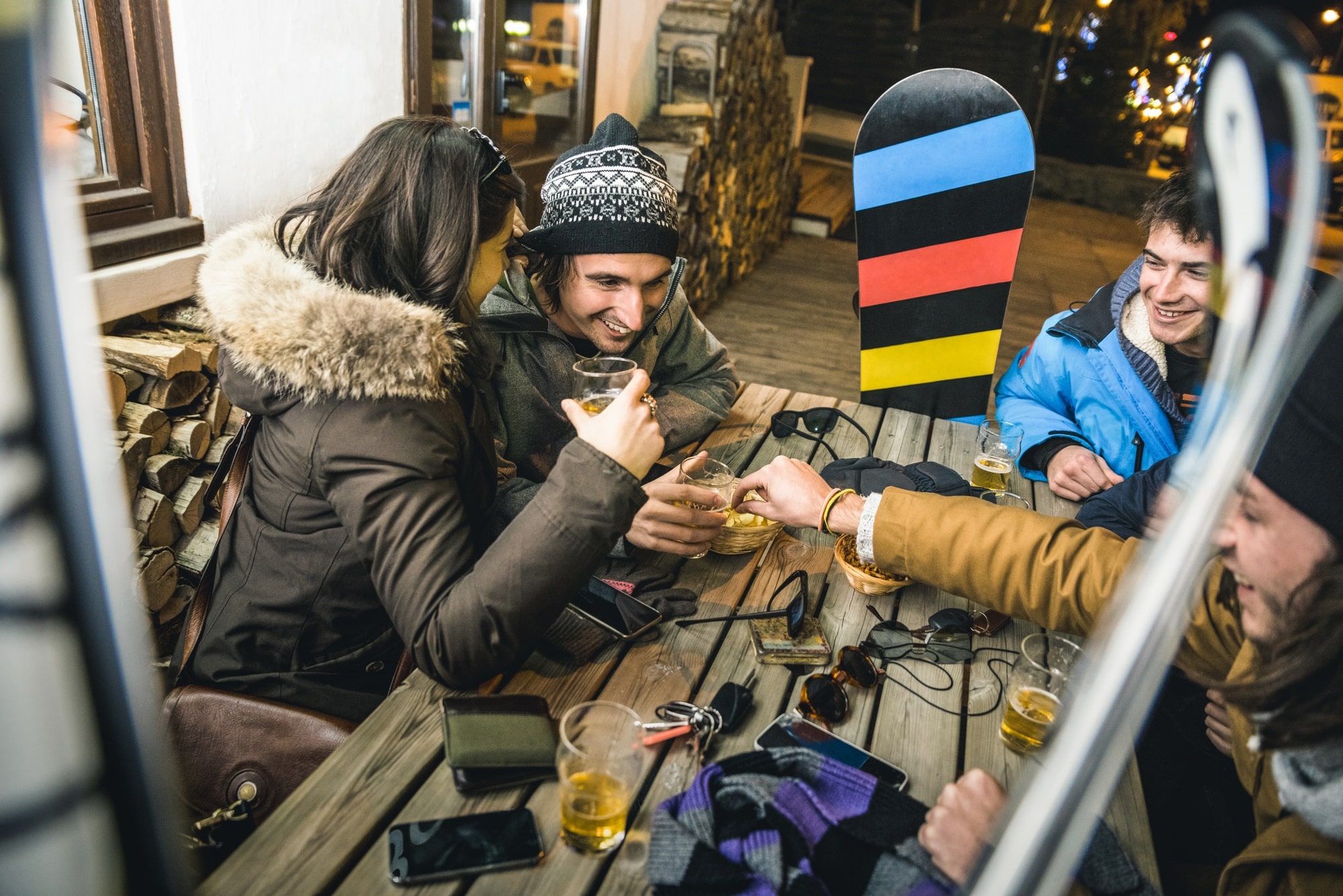 Happy friends drinking beer and eating chips at apres ski